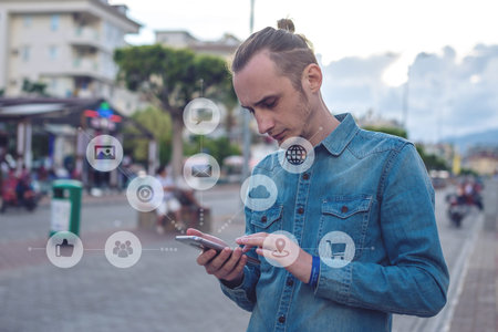 A man uses a smartphone to access social digital media in the Internet: shopping, entertainment,...