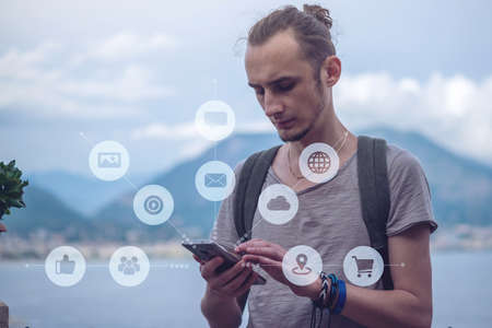 A man uses a smartphone to access social digital media in the Internet: shopping, entertainment, search and file storage. The concept of a global network expansionの写真素材