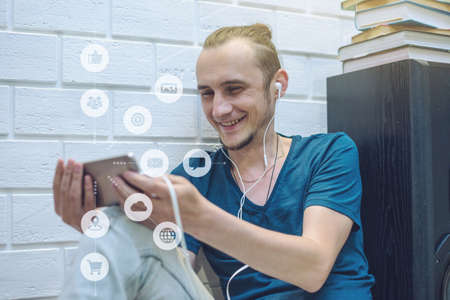 A man uses a smartphone to access social digital media in the Internet: shopping, entertainment, search and file storage. The concept of a global network expansionの写真素材