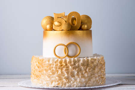 A beautiful cake for the 50th anniversary of the wedding decorated with gold balls and rings. The concept of festive dessertsの写真素材
