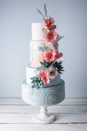 Beautiful home wedding four-tiered cake decorated with spring red flowers and handmade pattern. The...