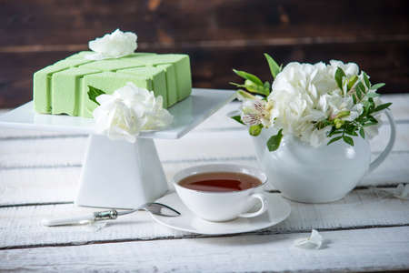Beautiful morning wedding tea table with a square green cake on the shelf and white hydrangeas. Desserts for a festive summer moodの写真素材