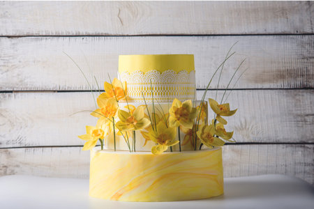 Beautiful home yellow wedding three-tiered cake decorated with red spring flowers. The concept...