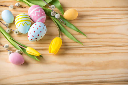 Colorful bright Easter eggs with yellow Tulip hand painted on a light wooden background. Festive spring cardの写真素材