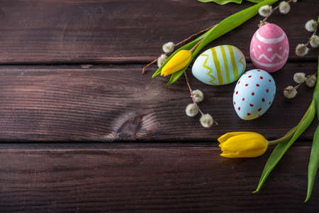 Colorful bright Easter eggs with yellow Tulip hand painted on a dark wooden background. Holiday spring cardの写真素材