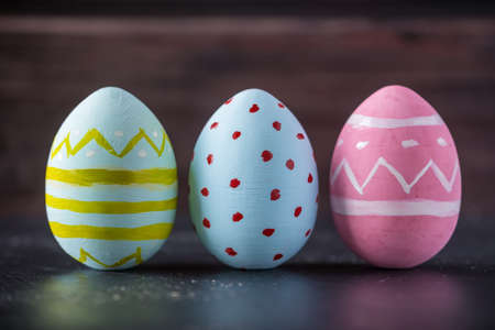 Colorful bright Easter eggs hand painted on a dark wooden background. Holiday spring cardの写真素材