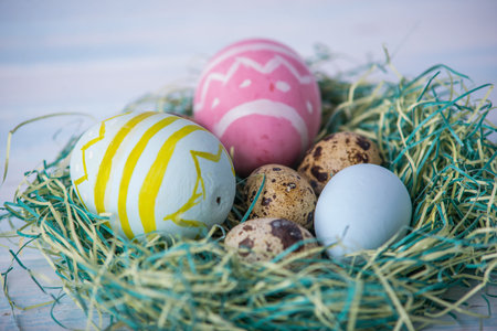 Colorful bright hand painted Easter eggs in a nest on a blue background. Holiday spring card