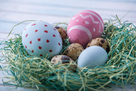 Colorful bright hand painted Easter eggs in a nest on a blue background. Holiday spring card