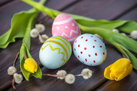 Colorful bright Easter eggs with yellow Tulip hand painted on a dark wooden background. Holiday spring cardの写真素材