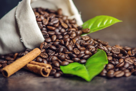 Pile of coffee beans and green leaves in bag on dark background. The concept of the production of fresh aromatic drink.の写真素材