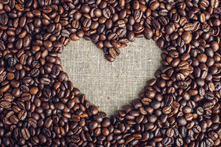 Textured background of coffee beans in heart-shaped top view. The concept love for a fresh and fragrant drink.の写真素材