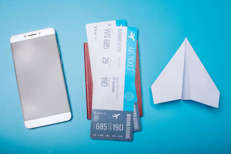 Air tickets with passport and paper plane on blue background, topview. Bright Pastel background. The concept of air travel and holidaysの写真素材