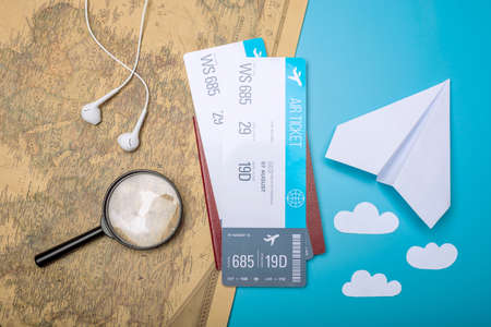 Air tickets with passport and paper plane on world map background, topview. Bright Pastel background. The concept of air travel and holidaysの写真素材