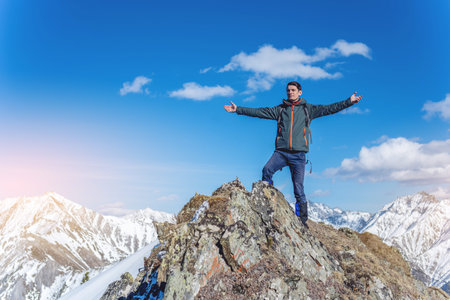 Male hikers tourist celebrating success standing on top, at the peak of a snowy mountain on a Sunny...