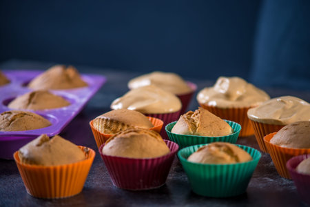 Homemade freshly made cupcakes in silicone molds on dark background. The concept of confectionery...