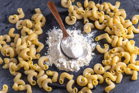 Uncooked italian pasta cavatappi with flour from durum wheat on a dark background. The concept of The composition of food design.の写真素材