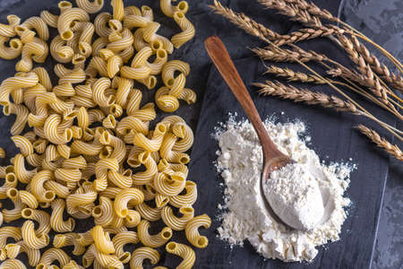 Uncooked italian pasta cavatappi with flour from durum wheat on a dark background. The concept of The composition of food design.の写真素材