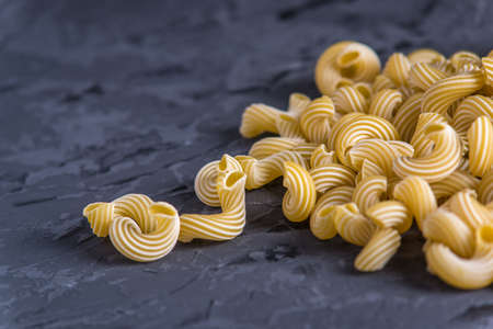 Uncooked italian pasta in the form of spirals on a dark background. The concept of composition of food design.の写真素材