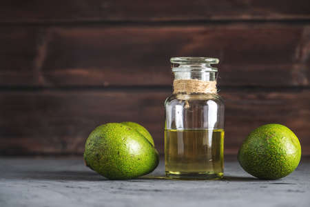 Green avocado fruit and oil in glass bottle on dark background. Concept organic eco products for food and cosmetic proceduresの写真素材