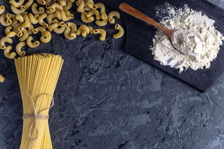 Uncooked italian pasta spaghetti and cavatappi with flour from durum wheat on a dark background. The concept of The composition of food design.の写真素材