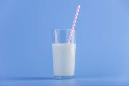 A glass of fresh milk with a straw on a blue background.の写真素材