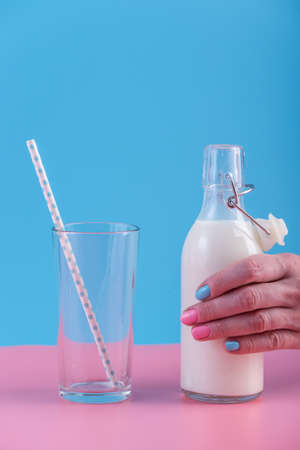 A woman's hand holds a bottle of fresh milk on a pastel background.の写真素材