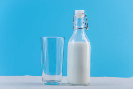 Glass bottle of fresh milk and glass on blue background.の写真素材