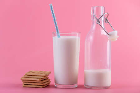 Glass bottle of fresh milk and cookies on pink background.の写真素材