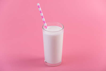 A glass of fresh milk with a straw on a pink background.の写真素材