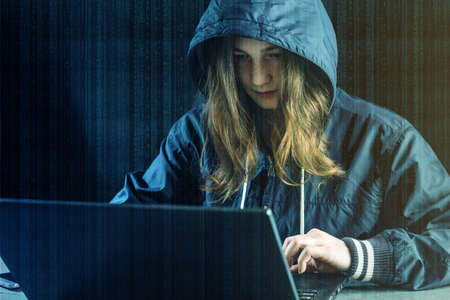 Girl hacker uses a laptop to hack the system. Stealing personal data.の写真素材