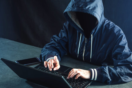 Anonymous hacker programmer uses a laptop to hack the system. Stealing personal data.