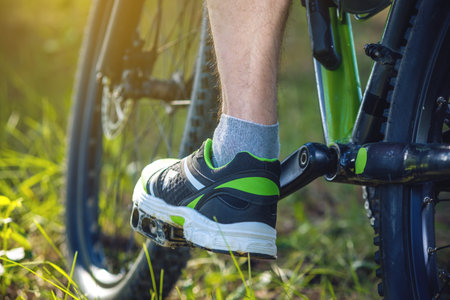 Cyclist on a green mountain bike in the woods riding on the grass. Bottom and back view. The concept...