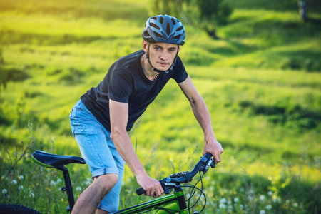 A man in a helmet riding on a green mountain bike in the woods among the trees. Cyclist in motion....