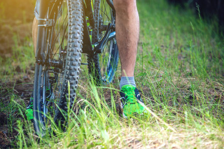 A man in a helmet riding on a green mountain bike in the woods among the trees. Cyclist in motion....