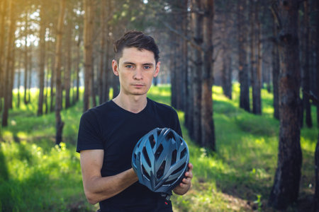 Man cyclist is wearing a sports gray helmet on his head in the background of green nature. The...