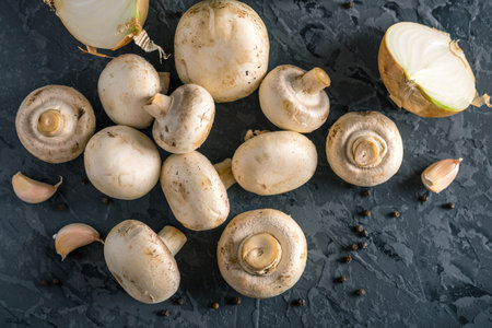 Fresh white Champions, spices and ingredients on the dark kitchen table. The concept of cooking...