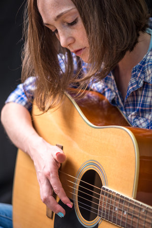 The girl teenager playing an acoustic guitar on a dark background in the Studio. Concert young musiciansの写真素材