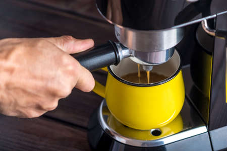 Preparation of espresso. Coffee pours from the coffee machine into the Cup. Professional coffee brewing at homeの写真素材