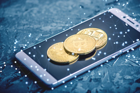 Physical bitcoin coin on the phone screen. The concept of cryptocurrency and blockchain in our life