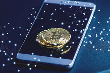 Physical bitcoin coin on the phone screen. The concept of cryptocurrency and blockchain in our lifeの写真素材