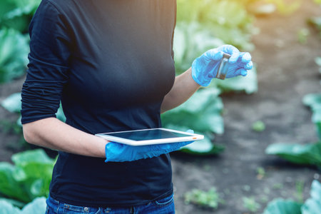 A young agronomist pretty woman holding a soil sample and a tablet. Concept environmentally friendly...