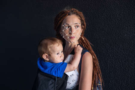 Biometric verification. Modern young woman with a baby. The concept of a new technology of face recognition on polygonal grid is constructed by the points of IT security and protectionの写真素材