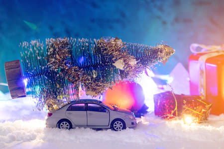 Toy car carries gifts in the Christmas and new year's eve on a blue background. The concept of holiday shopping and discountsの写真素材