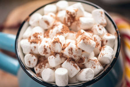 Mug of hot chocolate with marshmallow on top and Lollipop stick on wooden background. Cozy warm winter rustic compositionの写真素材