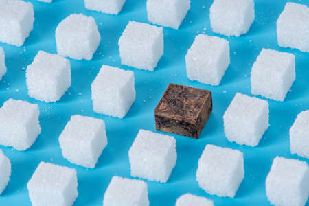 Pattern of sugar refined cubes and one chocolate blue background. The concept of harmful ingredient for confectioneryの写真素材