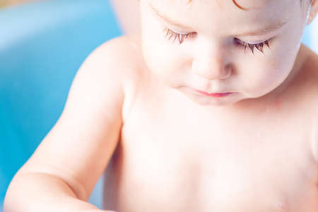 Mother washing head and hair little boy in a blue bath. Hygiene and water treatment at home with the babyの写真素材