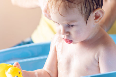 Mom washing little boy in a blue bath in the bathroom. Hygiene and water treatment at home with the...