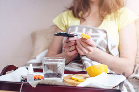 Woman with a cold chooses between pills and vitamins for treatment. Seasonal flu in winterの写真素材