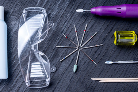A set of cosmetic tools for professional hardware manicure on a blue background. Milling cutter,...