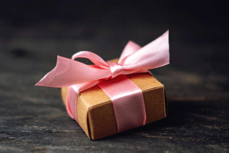 Holiday gift box Packed in crafting paper and red polka dots on dark wooden background. The concept of beautiful cards with giftsの写真素材